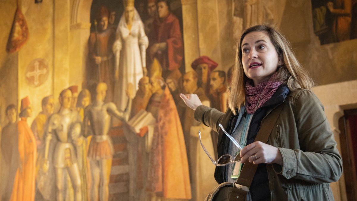 A tour guide at a museum explaining a painting.